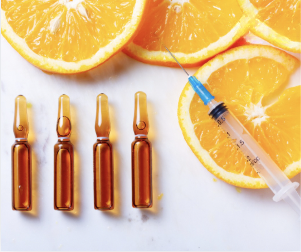 Vitamin injections: ampoules and syringe with oranges